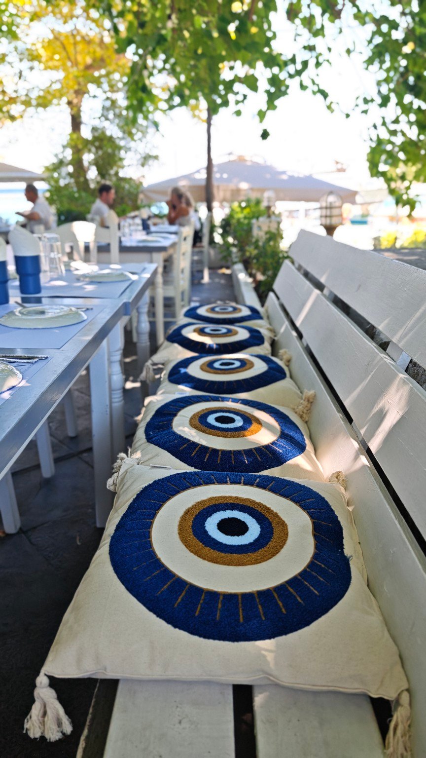 Blue eye-pattern cushions on a shaded taverna bench in the centre of Thassos town