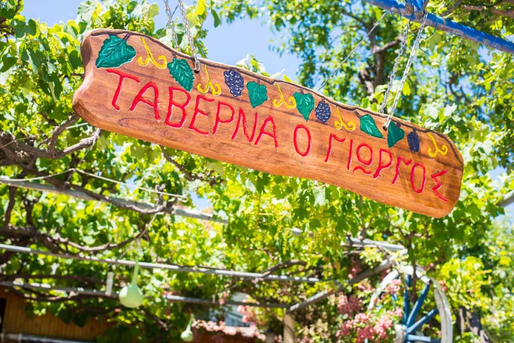 Wooden sign and greenery at Tavern Georgios in Potos
